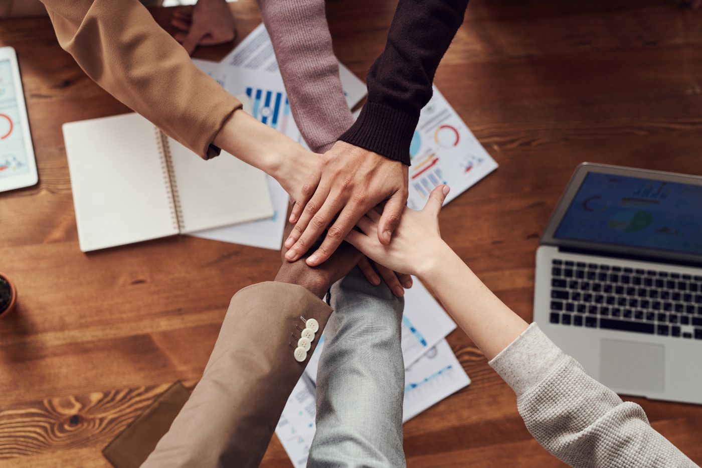 Many hands of different people joined together over a table