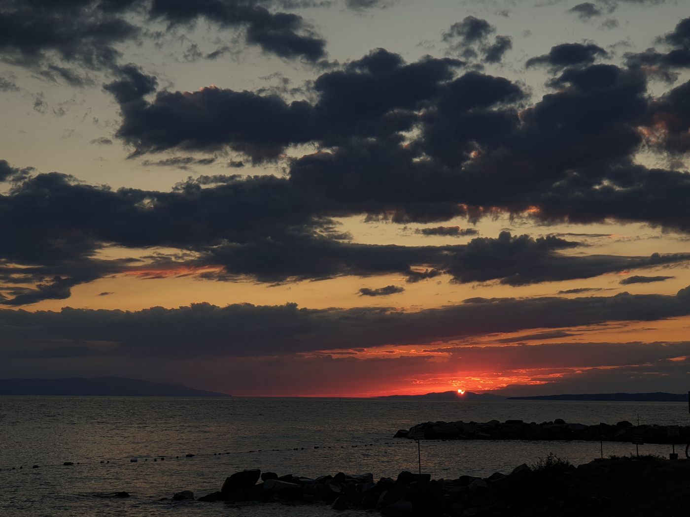 A golden sunset over water and distant hills